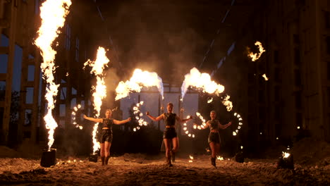 Espectáculo-De-Fuego-Profesional-En-El-Antiguo-Hangar-De-Los-Aviones:-Artistas-De-Circo-Profesionales,-Tres-Mujeres-Con-Trajes-De-Cuero-Y-Un-Hombre-Con-Dos-Lanzallamas.